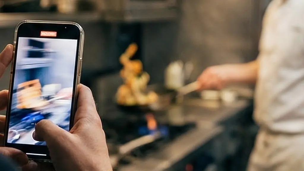 Chef en action filmé avec un smartphone pour les réseaux sociaux dans une cuisine moderne